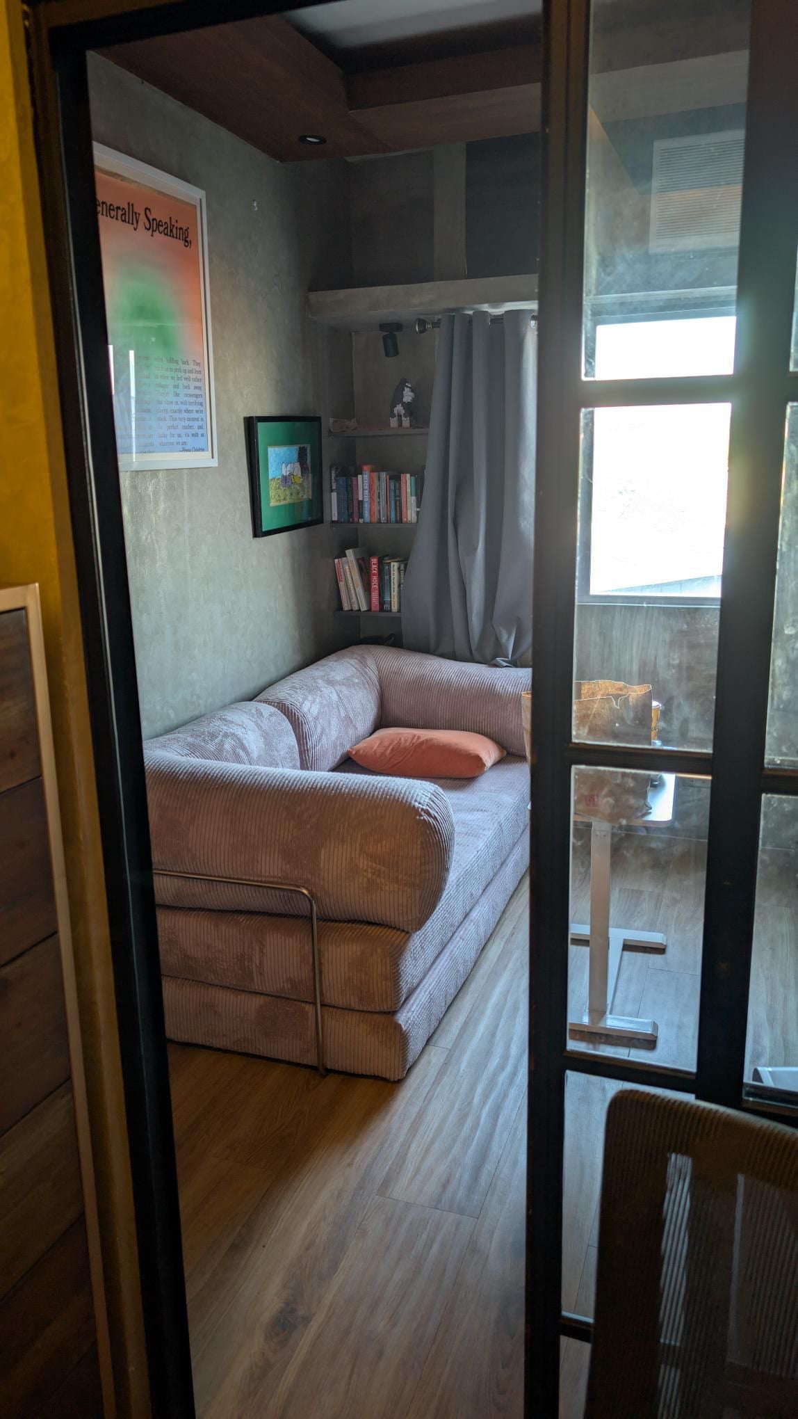 Compact home office with a pink Teddy sofa, wooden floors, bookshelves, and cozy Home Hues furniture