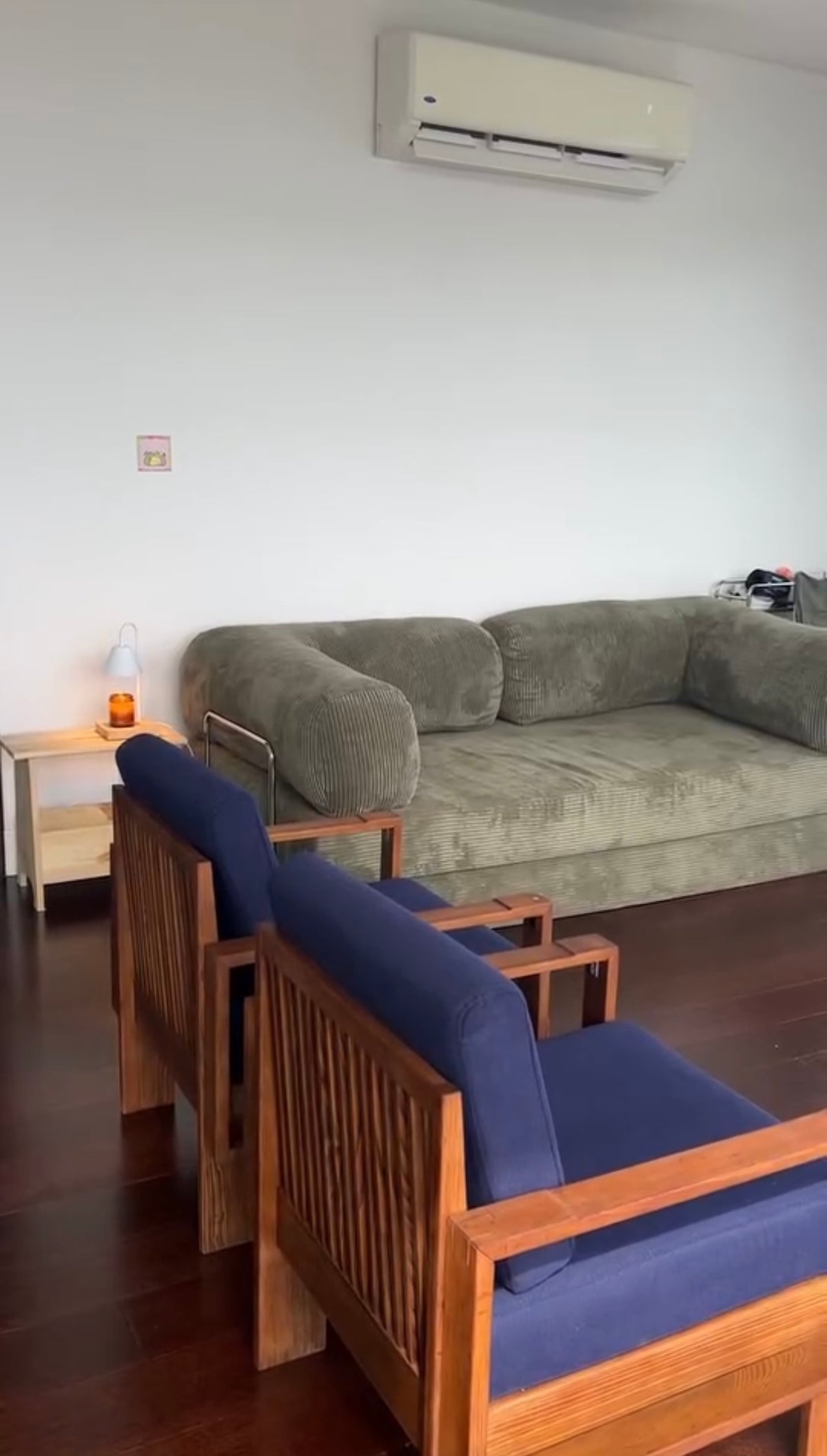 Spacious living room with green Teddy sofa, mid-century wooden armchairs with navy cushions, and stylish Home Hues furniture