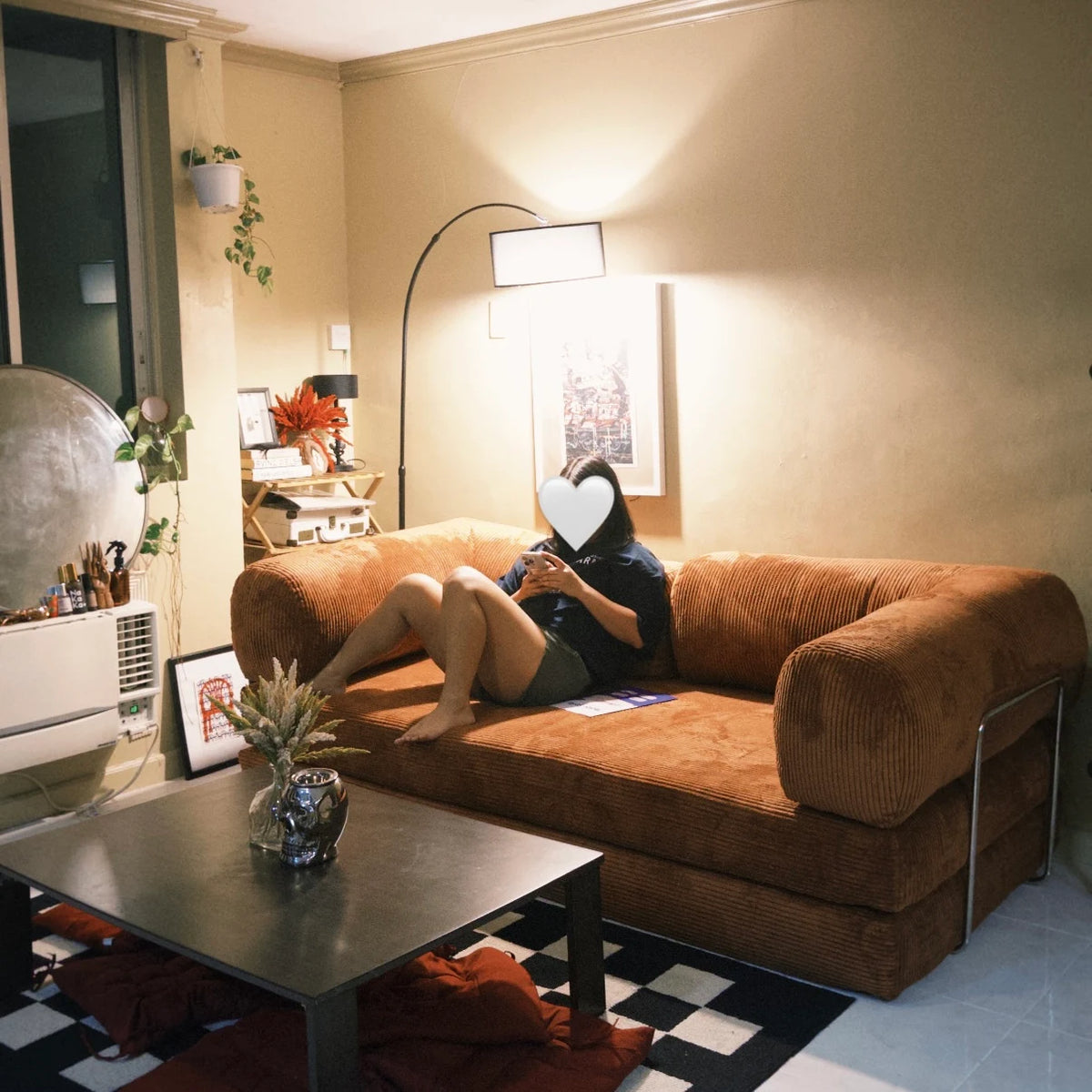 Rust orange Teddy sofa in a modern living room setup with checkered rug, black coffee table, and cozy Home Hues furniture